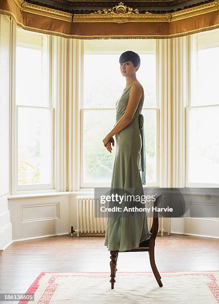 woman standing on chair in living room - evening wear stock pictures, royalty-free photos & images