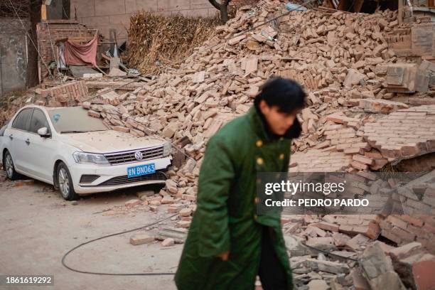 Man walks past a collapsed house in Dahejia in Jishishan County in northwest China's Gansu province on December 20, 2023. Survivors of China's...