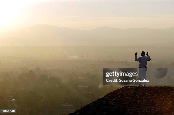 A man stands on a corner of the Pyramid of the Sun, raising his arms ...