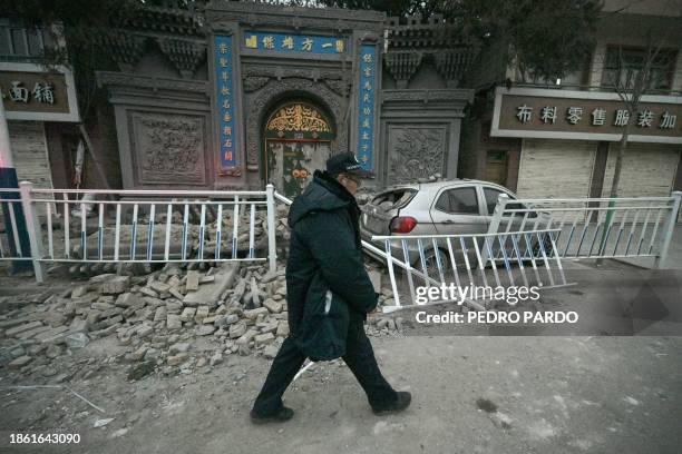 Man walks past a collapsed house in Dahejia in Jishishan County in northwest China's Gansu province on December 20, 2023. Survivors of China's...