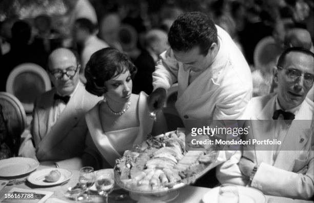 Waiter showing a platter to Italian actress Gina Lollobrigida. She's one of the stars at the Venice Film Festival. Venice, August 1959.