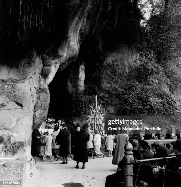 People praying in the Grotto of Massabielle during the centenary of the apparitions of Our Lady to Saint Bernadette Soubirous. Lourdes, 22nd November...