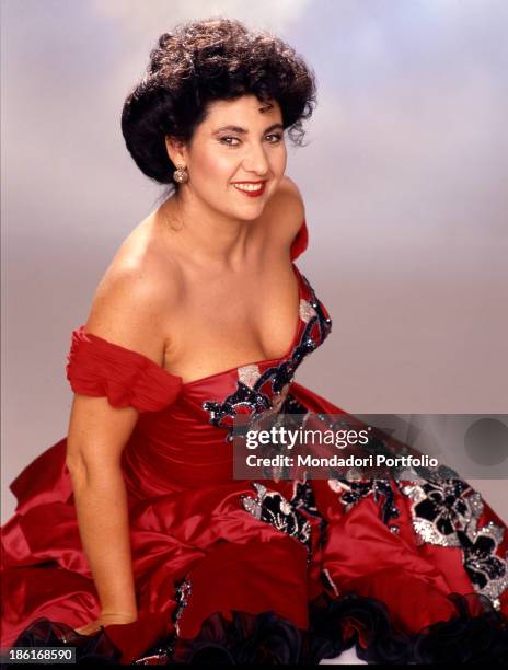 Italian actress, presenter and singer Marisa Laurito wearing a red low-necked dress. 1987.