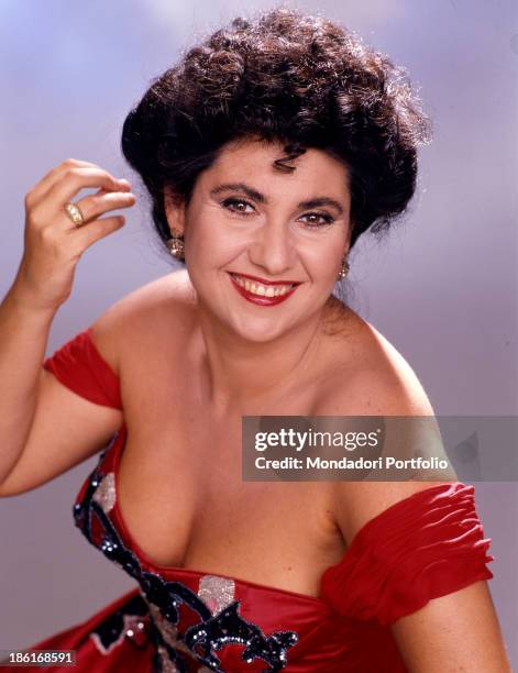 Italian actress, presenter and singer Marisa Laurito smiling in a red low-necked dress. 1987.