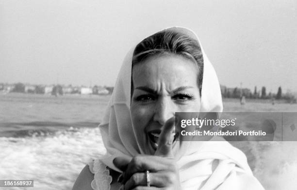 Mexican actress Maria Félix gesticulating on a boat with a scarf around her head. She's taking part in the Venice Film Festival. Venice, August 1959.