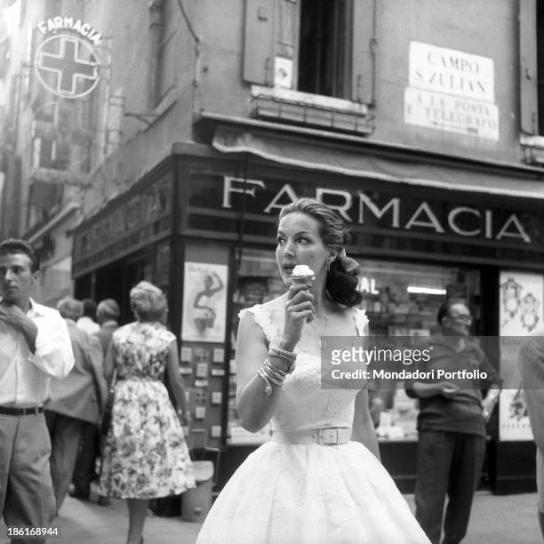 Mexican actress Maria Félix eating an ice cream in front of a pharmacy in Campo San Zulian. She's taking part in the Venice Film Festival. Venice,...
