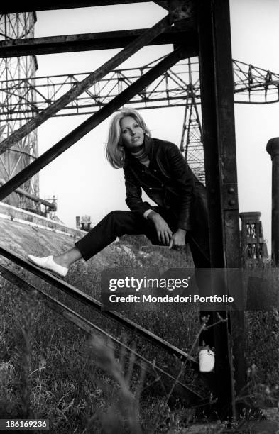 Italian TV presenter and actress Gabriella Farinon smiling leaning on a pylon. Italy, 1968.