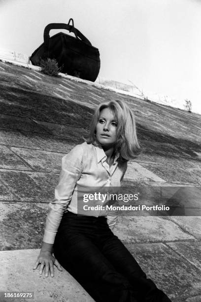 Italian TV presenter and actress Gabriella Farinon sitting on a river bank. Italy, 1968.