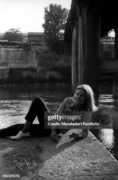 Italian TV presenter and actress Gabriella Farinon smiling lying on a river bank. Italy, 1968.