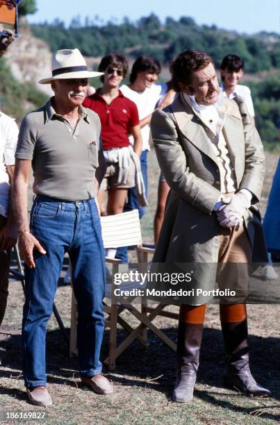 Italian director Mario Monicelli standing with hat and sunglasses beside Italian actor and director Alberto Sordi on the set of the film The Marquis...
