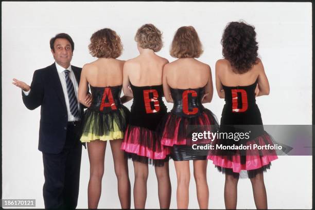 The anchorman Emilio Fede is standing next to four girls of the tv quiz broadcast Test; the girls are seen from their back to show the letter they...
