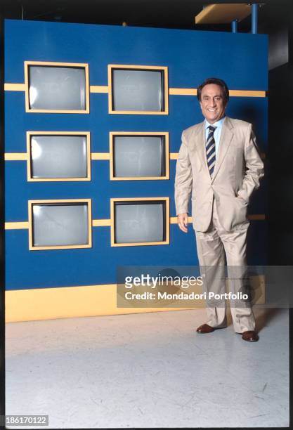 The director and anchorman of Tg4 Emilio Fede is smiling, a hand in pocket, next to some monitors of the studio. Milano 2, Segrate , Italy, 1994.