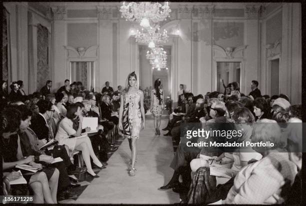 Model wearing a patterned dress and a pair of flip-flop catwalking at Palazzo Pitti. Florence, 1960s.