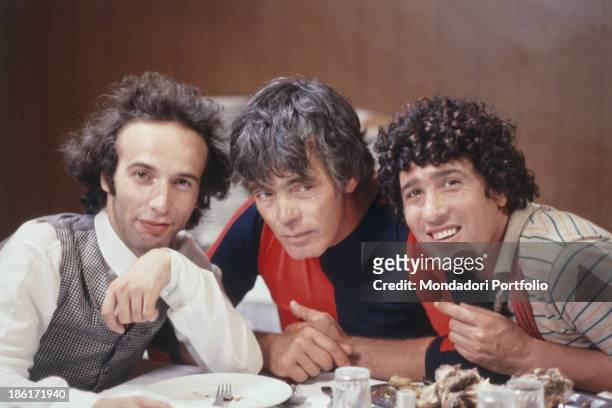 Italian actor and director Roberto Benigni, Italian actor and director Franco Citti and Italian actor Ninetto Davoli sitting at the table on the set...