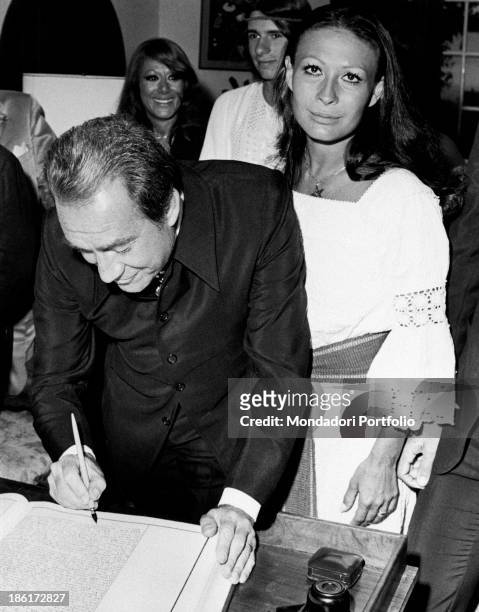 Ugo Tognazzi puts his signature on the register during the wedding ceremony with Franca Bettoja; behind the bride there are Ricky, son of Ugo and the...