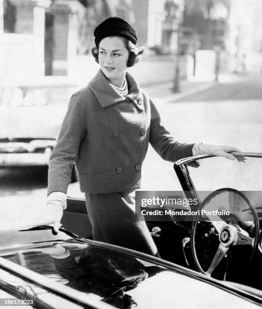 Italian countess, model and fashion editor Consuelo Crespi, born Consuelo O'Brien O'Connor Crespi, gets in a convertible car, dressed in a Chanel...