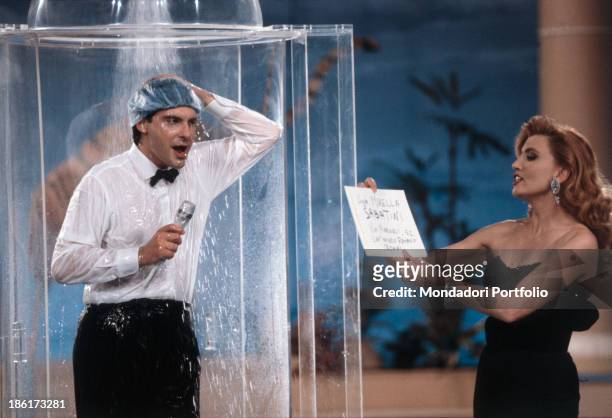 Italian TV presenter Milly Carlucci reading a sheet while Italian TV presenter and dubber Fabrizio Frizzi is having a shower dressed in the TV show...