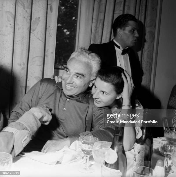 Italian racing car and moto driver Piero Taruffi and his wife Isabella Taruffi smiling seated at the table at the Mille Miglia Automobile Race....