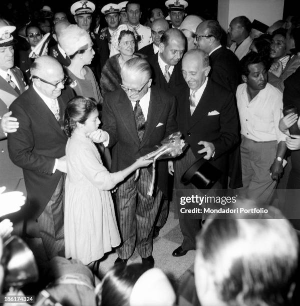 The President of the Italian Republic Giovanni Gronchi, beside the President of Peru Manuel Prado Ugarteche, caresses a girl who is giving him a...