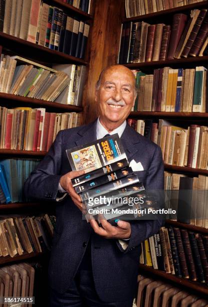 Italian publisher and playwright Valentino Bompiani, executive of the review Sipario, in his library holds in his hands a few volumes of Dizionario...