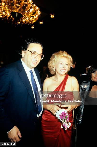 Italian actress and TV presenter Sandra Milo in an evening dress smiling beside Italian politician Gianni De Michelis. 1980s.