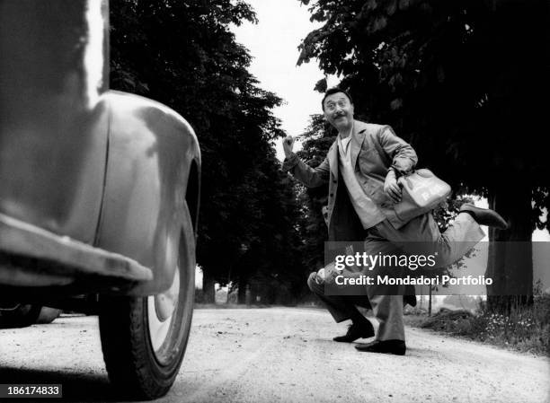 Italian actor and comedian Erminio Macario hitchhiking in a comic gag. Italy, 1960s.