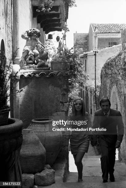 Italian TV and radio presenter Mike Bongiorno and his partner, the Italian journalist and art director Annarita Torsello, walking hand in hand....