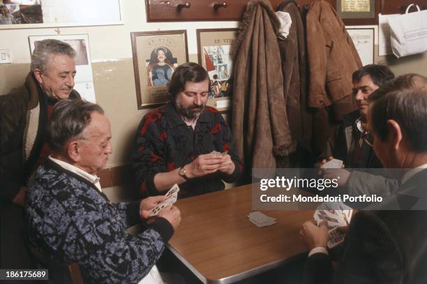 Italian musician, singer-songwriter and writer Francesco Guccini playing cards seated in a tavern. Italy, 1987.