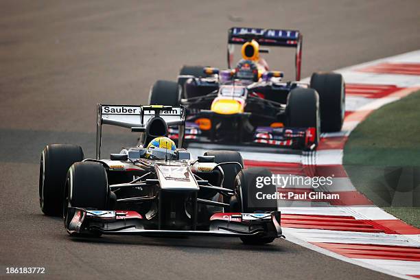 Esteban Gutierrez of Mexico and Sauber F1 drives ahead of Sebastian Vettel of Germany and Infiniti Red Bull Racing during the Indian Formula One...