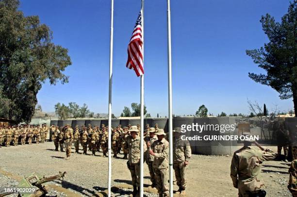 Army personnel lower their national flag at a ceremony to mark the handover of the base to Italian troops at Camp Salerno, near Khost, 15 March 2003....