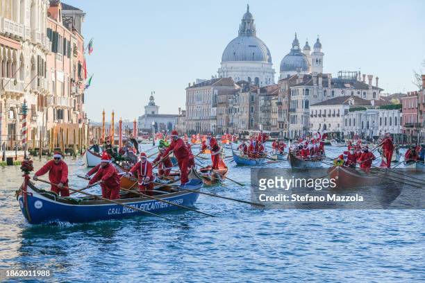 Boats carrying rowers dressed as Santa Claus sail down the Grand Canal during the Christmas water pageant on December 17, 2023 in Venice, Italy.