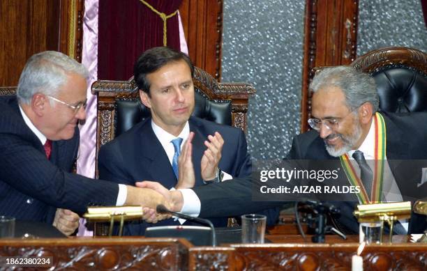 Bolivian Vice President, Carlos Mesa Gisbert , streches his hand to greet the new President, Gonzalo Sanchez de Lozada, as former President Jorge...