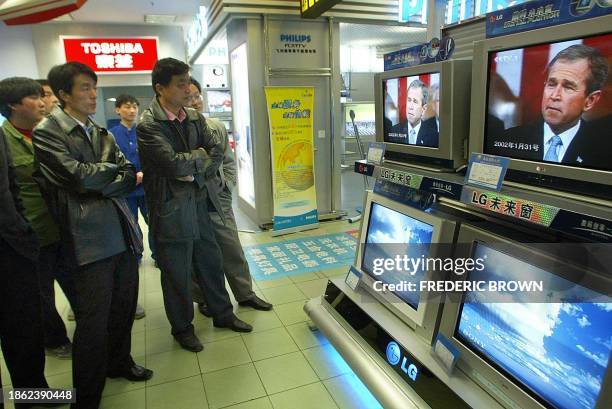 People in a Beijing department store watch a CCTV broadcast on the Iraq War as US President George W. Bush appears from an earlier speech on...