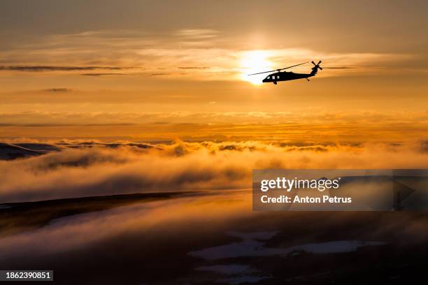 utility military helicopter over a misty landscape at sunset - attack helicopter stock pictures, royalty-free photos & images