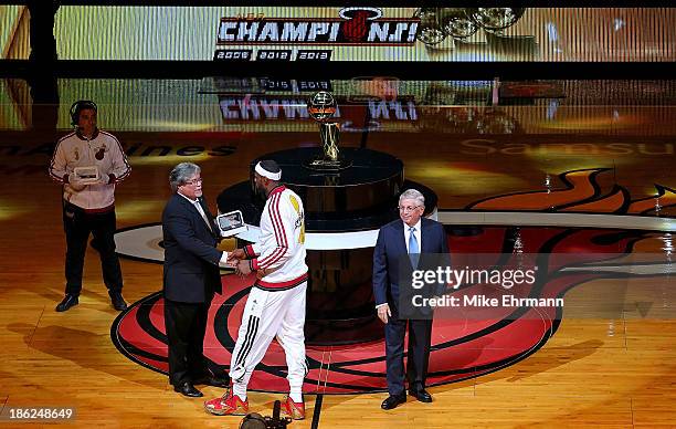 LeBron James of the Miami Heat recieves his 2013 Championship Ring from owner Micky Arrison and NBA commissioner David Stern during a game against...