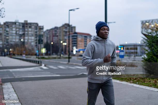 young man jogging in city at dawn - bjelica stock pictures, royalty-free photos & images