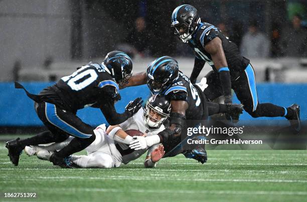 Desmond Ridder of the Atlanta Falcons is tackled by Deion Jones and Derrick Brown of the Carolina Panthers during the first half of the game at Bank...