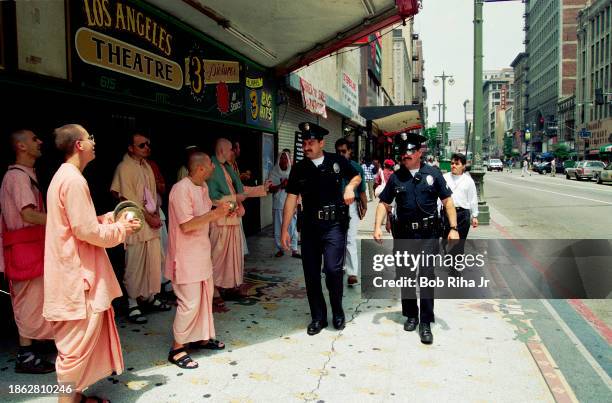 Los Angeles Police Department officers on foot patrol walk past a group of chanting individuals, May 19, 1995 in downtown Los Angeles, California.