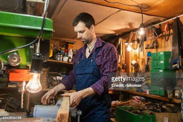carpentry shop worker - young handyman in old home workshop working with vise grip for woodworking - handyman overalls stock pictures, royalty-free photos & images