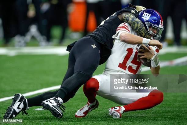 Tommy DeVito of the New York Giants is sacked by Demario Davis of the New Orleans Saints during the first half of the game at Caesars Superdome on...
