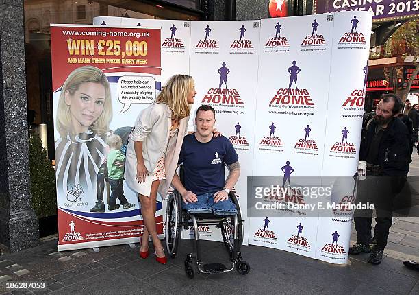 Sarah Harding and Private Michael Swain attend a photocall to launch the Coming Home lottery ticket at Hippodrome Casino on October 30, 2013 in...