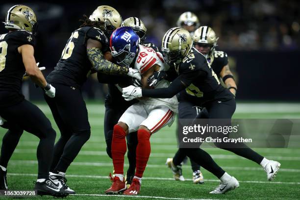 Gunner Olszewski of the New York Giants is tackled by Paulson Adebo and Demario Davis of the New Orleans Saints during the second half of the game at...