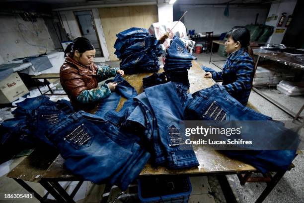 Workers sew blue jeans in a little workshop by the street on February 10, 2012 in Xintang, Guangdong province, China.The town of Xintang, nicknamed...