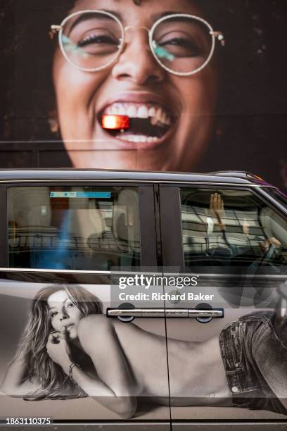 Taxi ad and a billboard for a new optician retailer outlet for Vision Express on Oxford Street on 20th December 2023, in London, England.