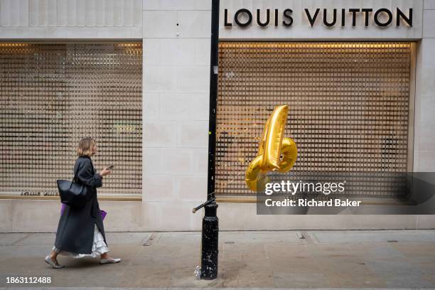 Christmas shoppers and helium balloons tied to a lamp post outside Louis Vuitton on New Bind Street on 20th December 2023, in London, England.