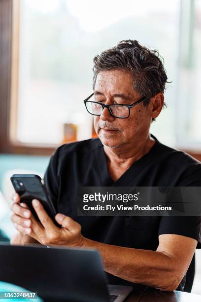 dentist on his phone while in office - pacific islanders stock pictures, royalty-free photos & images