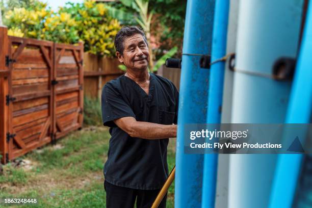 aktiver senior, der surfbretter auf das auto lädt, bevor er zur arbeit geht - hawaiianischer-abstammung stock-fotos und bilder