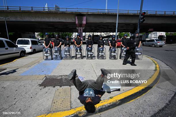 Homeless man lies on the street in front of anti-riot police officers in Buenos Aires, on December 20, 2023. Argentina is commemorating these days...