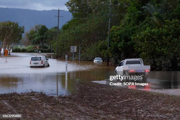Man in a car attempts to cross a flooded road in the evening on the inundated suburb of Holloways Beach. Major flooding was brought by intense rain,...