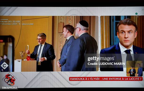 This photograph taken on December 20, 2023 shows a television screen broadcasting French TV channel France 5 as French President Emmanuel Macron...